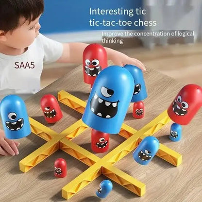 Child playing with a toy tic-tac-toe game featuring colorful monster pieces on a wooden surface.