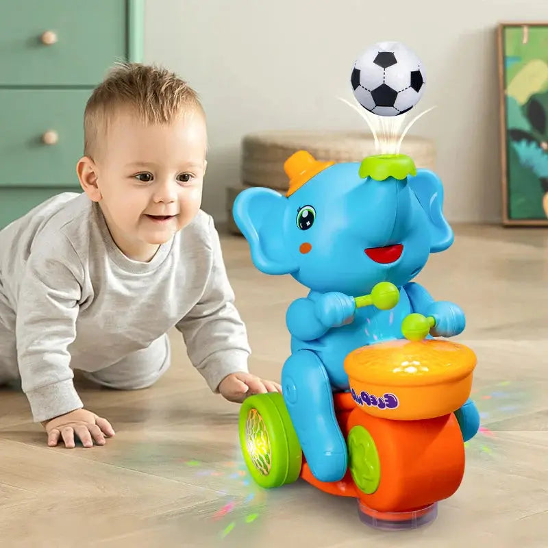 A baby elephant toy with a soccer ball on top, featuring colorful lights and music, being played with by a toddler.
